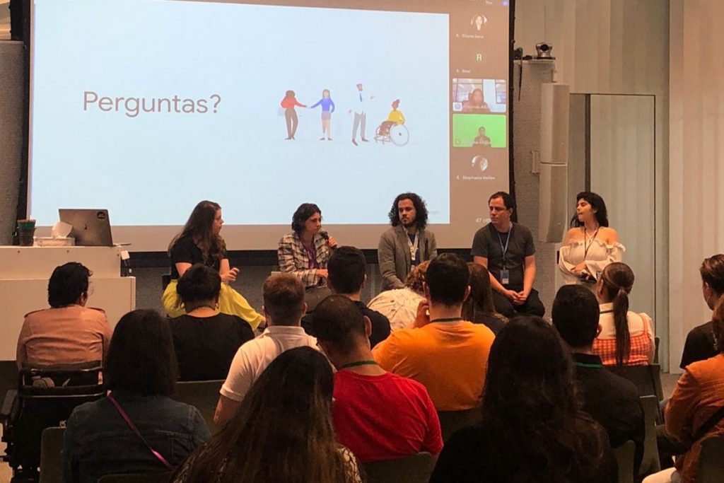 Foto tirada no local do evento de hoje no Google Brasil. Há cinco porta-vozes da empresa em frente a um grupo de cerca de 15 pessoas em uma sala fechada.